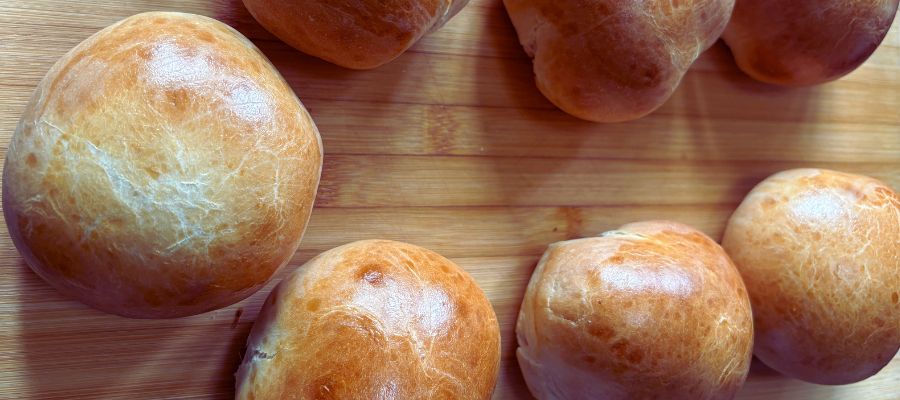 Golden homemade burger buns baked with caramelized ghee, cooling on a wooden board – easy ghee bread recipe from Calgary.